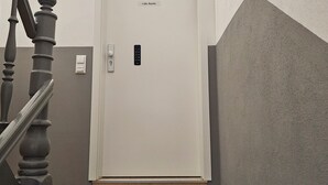 A staircase with a wooden handrail and a white door with a keypad lock. - Schöne Groß Ferienwohnung 78m² Ideal für Familie 3 Schlafzimmer Zentrumnah 1.og (Erfurt)