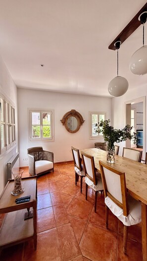 A dining area with a wooden table, chairs, and a vase of flowers.