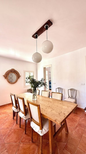A dining room with a wooden table, chairs, a vase with flowers, a mirror, and a ceiling fan. - Villa in Nature with Yoga Room, Peace and Tranquility (Puigpuñent)