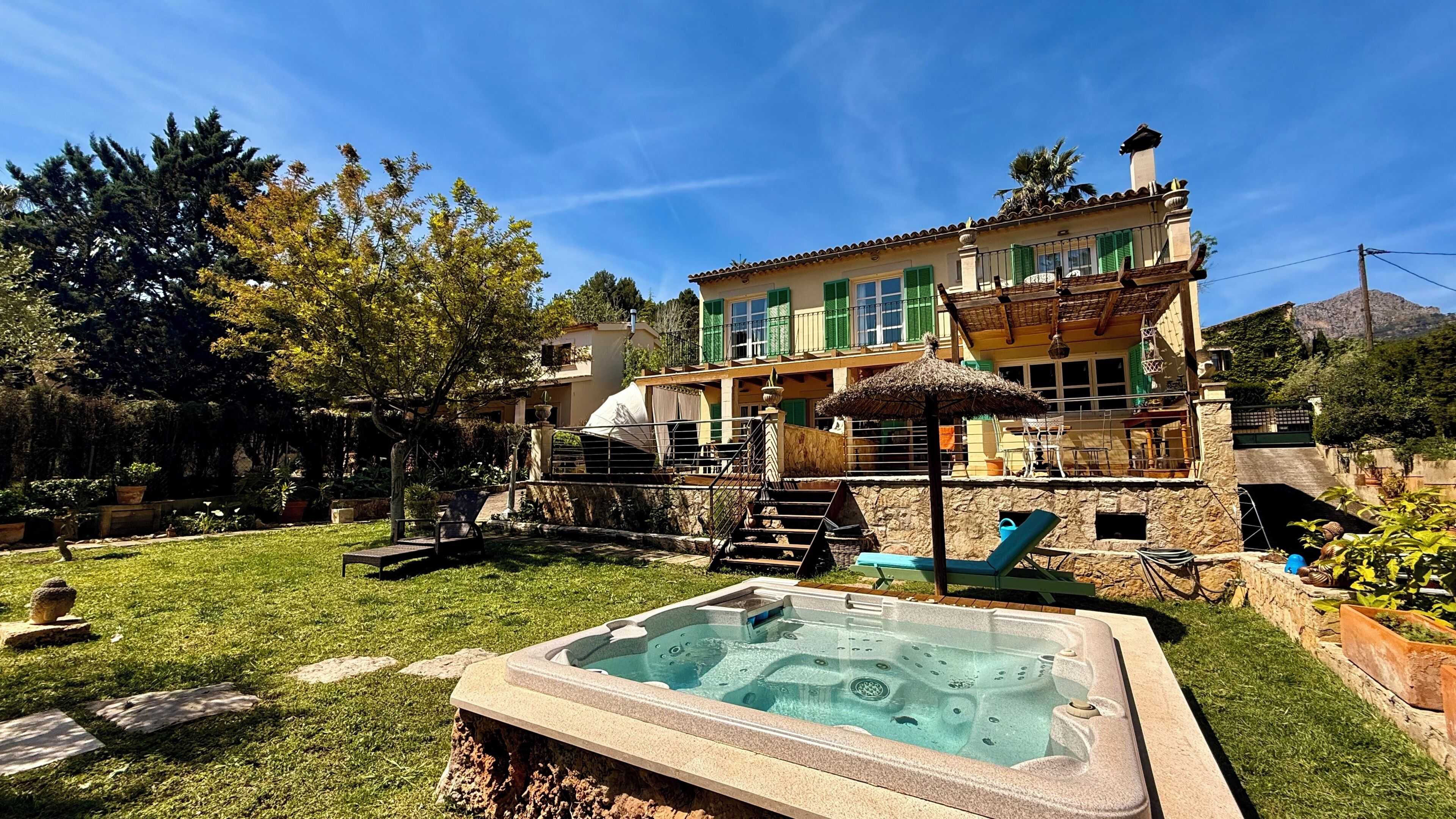 Een tweelaags huis met een jacuzzi in de achtertuin, een trap en een terras.