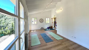 A spacious room with large windows, wooden flooring, and yoga mats. - Villa in Nature with Yoga Room, Peace and Tranquility (Puigpuñent)