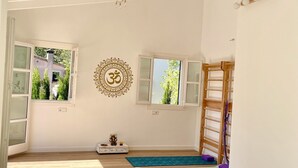 A yoga studio with wooden floors, yoga mats, a wooden ladder, and a wall-mounted decorative item. - Villa in Nature with Yoga Room, Peace and Tranquility (Puigpuñent)