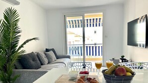 A modern living room with a sofa, a dining table with breakfast items, and a balcony with a view. - Apartment 3 bedrooms 3 min to beach (Cannes)