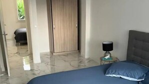 A bedroom with a large bed, a wardrobe, and a nightstand with a lamp. - Apartment 3 bedrooms 3 min to beach (Cannes)