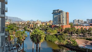 A high-rise hotel with a view of a water body and palm trees. - Modern Century City Apartment - Mountain Views (Cape Town)