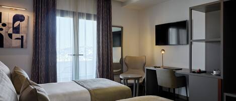 A hotel room with two beds, a desk, a chair, a TV, and a large window with curtains.