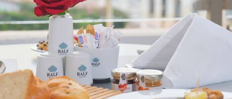 Desayuno con bollos, una rosa y condimentos del hotel RALF.