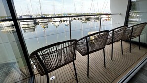 A deck with four wicker chairs and a view of a marina with multiple sailboats. - Island Harbour Houseboat (Binfield)