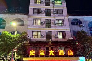 Un hôtel à plusieurs étages, doté de climatiseurs et d’une enseigne lumineuse.