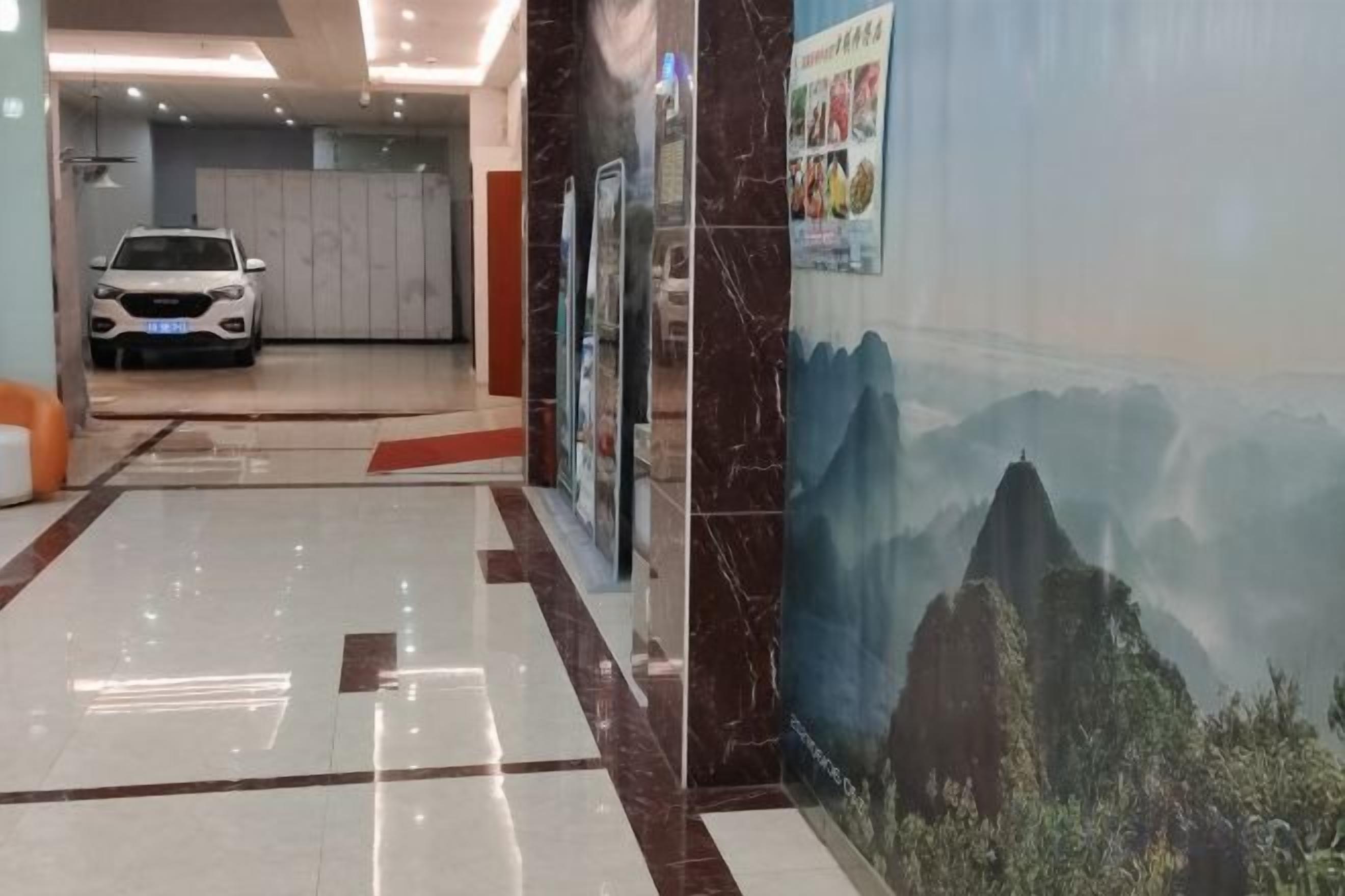 A hotel corridor with a white car parked in the background, a marble floor, and a mural of a mountain landscape.