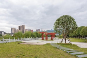 A park with a red pavilion, a tree, and a pathway. - Pinshang Holiday Hotel (Libo)