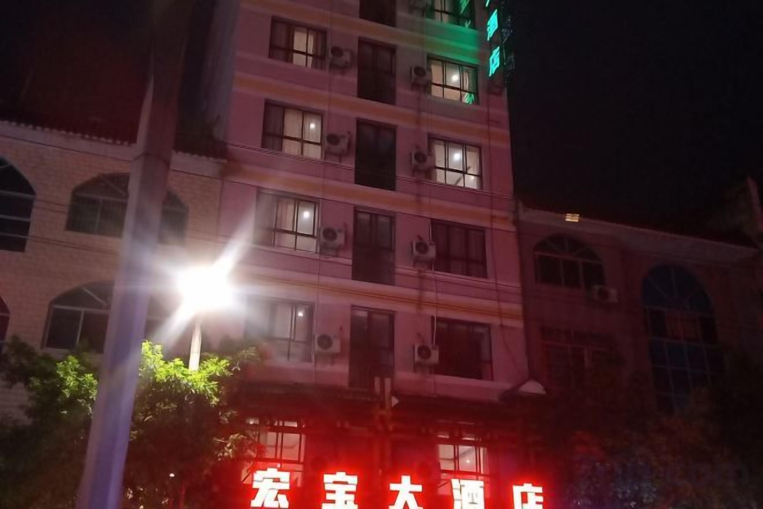 A multi-story building with illuminated signage, air conditioning units, and a street lamp.