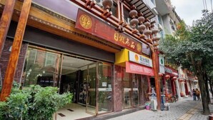 Un edificio tradicional chino con escaparate que presenta grandes ventanales y un letrero rojo con caracteres dorados.