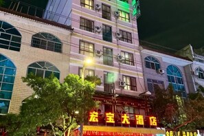 A multi-story building with large windows and a sign in the foreground.
