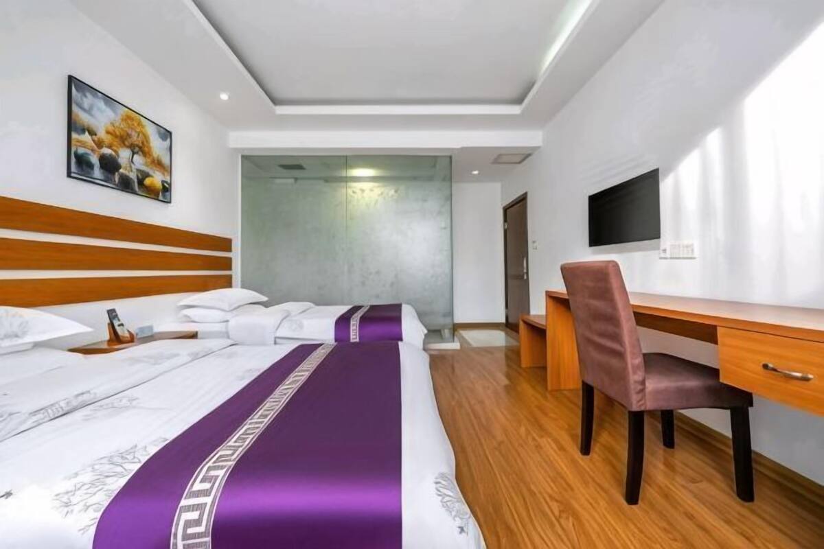 Una habitación de hotel con cama, escritorio, silla, televisor y un cuadro en la pared.