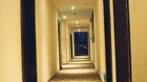 Un pasillo estrecho, alfombrado con un piso estampado, que conduce a una puerta al final.