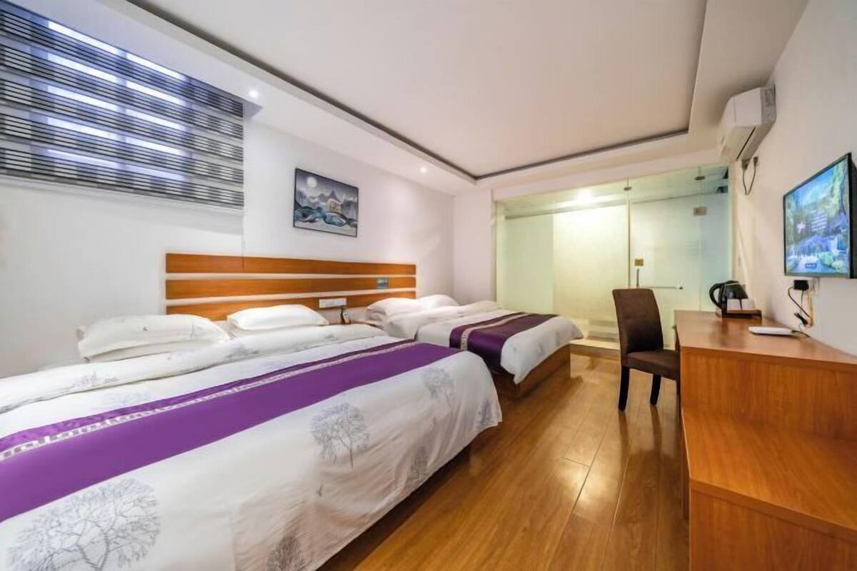 Una habitación de hotel con dos camas, un escritorio, una silla y un televisor.