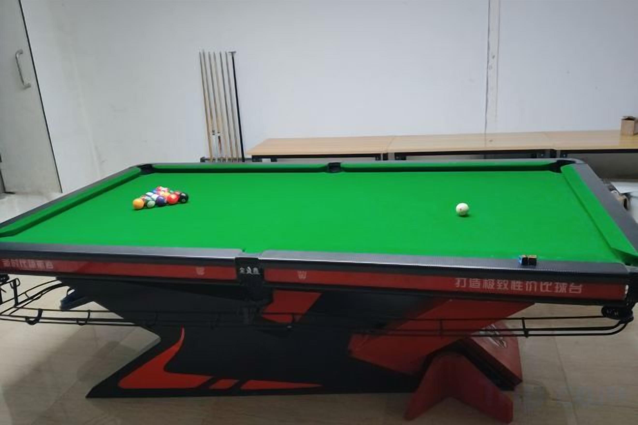 A pool table with balls, a green felt surface, and a red and black table base.