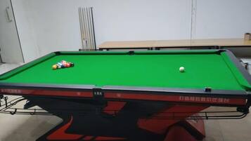 A pool table with balls, a green felt surface, and a red and black table base.