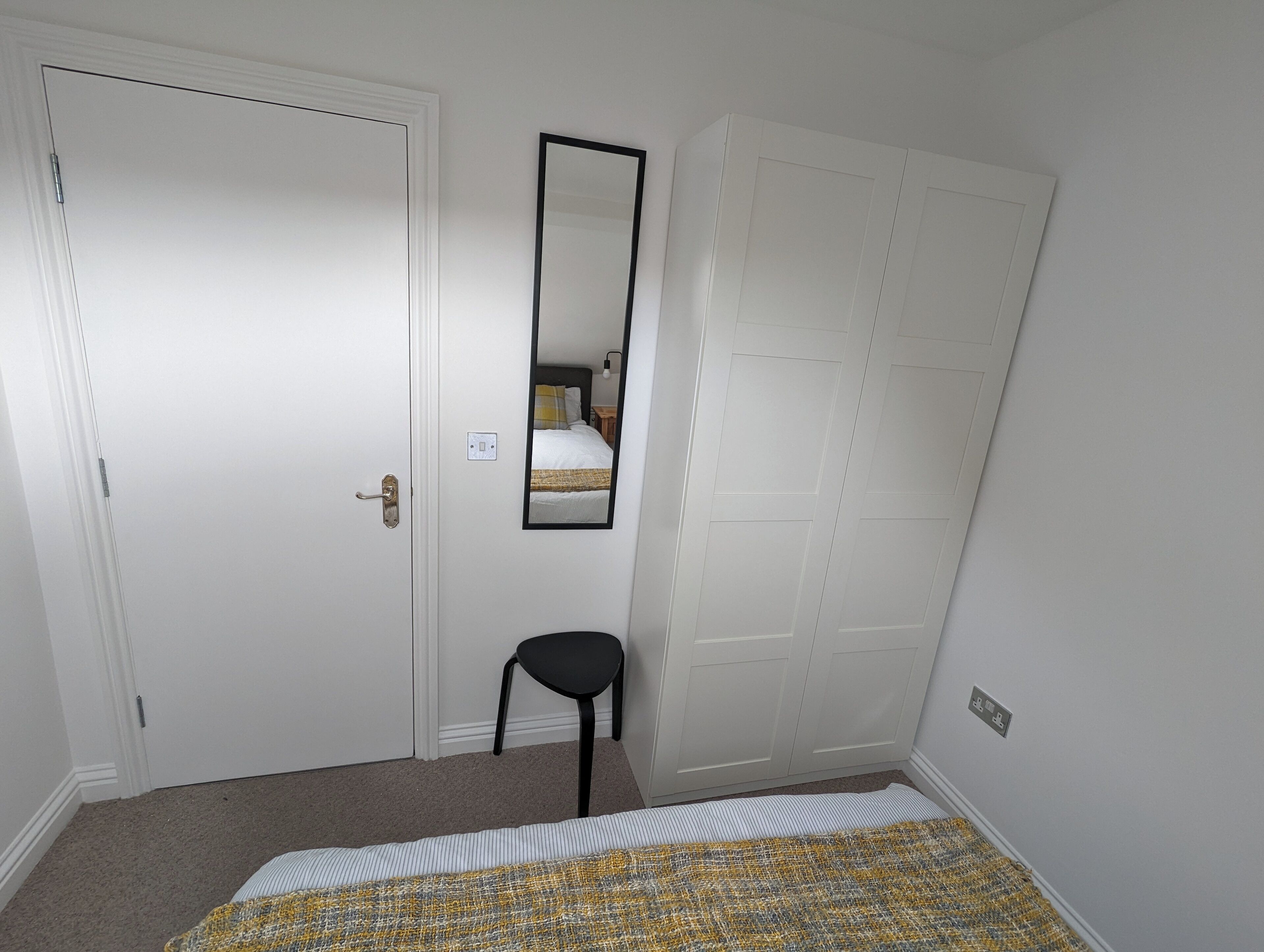 Ein Schlafzimmer mit Bett, Stuhl, Kleiderschrank und Spiegel.