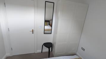 Ein Schlafzimmer mit Bett, Stuhl, Kleiderschrank und Spiegel.