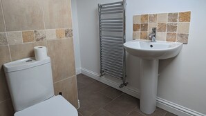 A bathroom with a toilet, a sink, and a towel rack. - Top Floor Apartment (Llandudno)