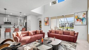 A modern living room with two sofas, a coffee table, and a dining area with chairs.