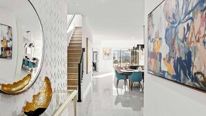 A modern interior with a staircase, a dining area, and abstract art.