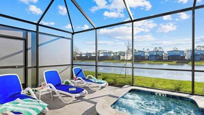 A glass-enclosed outdoor area with lounge chairs and a hot tub.