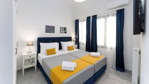 Une chambre d’hôtel avec un grand lit, une table de chevet, une lampe, un climatiseur et un téléviseur.