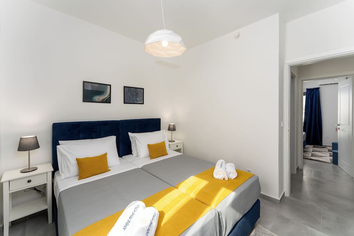 Una habitación de hotel moderna con una cama grande, dos mesitas de noche y una lámpara colgante.