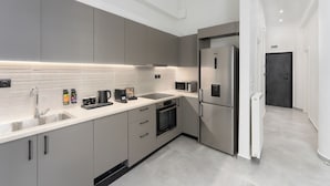 Une cuisine moderne avec des meubles gris, des appareils en acier inoxydable et un plan de travail élégant.