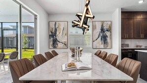 Un espace repas moderne avec une table en marbre, des chaises en cuir et des œuvres d’art abstraites accrochées aux murs.