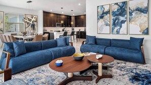 Un salon moderne avec un canapé bleu, une table basse en bois et des œuvres d’art abstraites accrochées au mur.