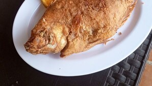 A table with two plates of food, one with rice and vegetables, and the other with a whole fried fish. - Balneario manantial  (San Pablo de Borbur)