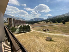 A view from a balcony overlooking a mountainous landscape with a large building and a road.