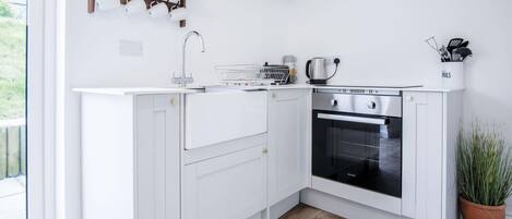 Une cuisine moderne avec des meubles blancs, un four encastré et une machine à café.