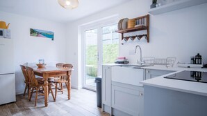 Una cocina moderna con comedor, que incluye una mesa y sillas de madera, horno empotrado y un amplio ventanal con vistas al exterior.