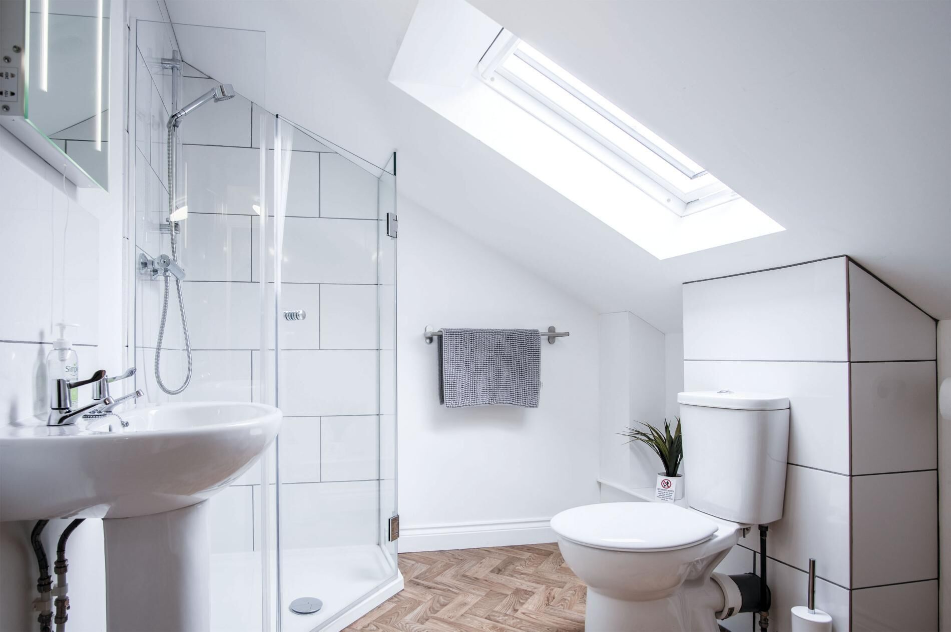 Een moderne badkamer met dakraam, douche, toilet en wastafel.