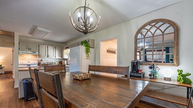 A spacious kitchen with a large wooden table, a chandelier, and a view through a large arched window. - Stroll to Park, Shops, Restaurants in Downtown WJ! (West Jefferson)