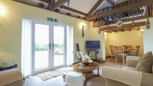 Una sala de estar acogedora con chimenea, televisor y comedor con muebles de madera.