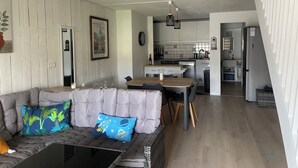 A modern living room with a grey sofa, a coffee table, and a dining area with a wooden table and chairs. - Bel Appartement Familial en Duplex, à 2 min à Pied de la Plage (ARZON (56640))