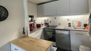 A compact kitchen with white cabinets, a dishwasher, a sink, and a wooden countertop. - Bel Appartement Familial en Duplex, à 2 min à Pied de la Plage (ARZON (56640))
