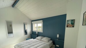 A bedroom with a bed, bedside tables, a window, and a painting on the wall. - Bel Appartement Familial en Duplex, à 2 min à Pied de la Plage (ARZON (56640))