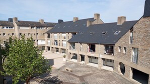 A courtyard with stone buildings, a tree, and a bench. - Bel Appartement Familial en Duplex, à 2 min à Pied de la Plage (ARZON (56640))