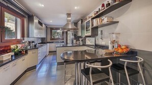 A modern kitchen with a central island, stainless steel appliances, and a view of the outdoors.