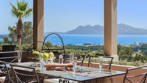 A table set for two with a view of the sea and mountains.