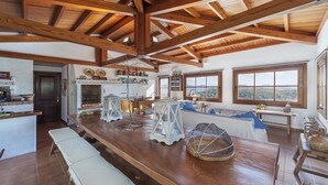 A spacious kitchen with wooden beams, a large island, and a view of the outdoors.