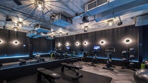 A modern gym with mirrored walls, various exercise equipment, and a central bench. - Lux Superior Studio - Cinema, Gym, Roof Terrace (London)