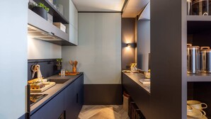 A modern kitchen with built-in cabinets, a herringbone floor, and a variety of kitchenware and utensils. - Lux Superior Studio - Cinema, Gym, Roof Terrace (London)